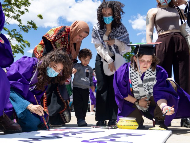 Several dozen graduates and supporters paint messages outside for Palestinian victims of the war in Gaza after walking out in protest during Northwestern University's commencement on June 9, 2024, at the United Center. (Brian Cassella/Chicago Tribune)