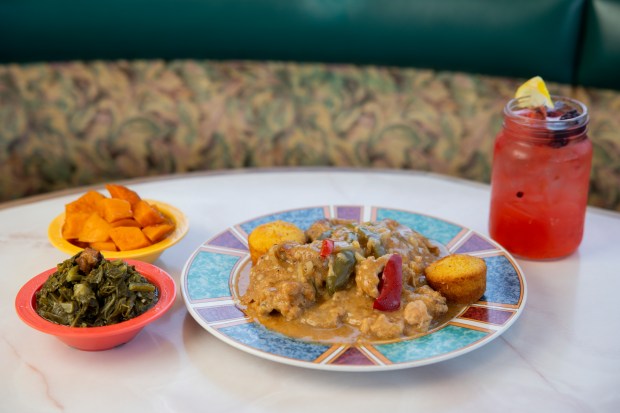 A plate of smothered pork chops, corn muffins with sides of slick mustard greens and candied yams, and a strawberry lemonade on June 7, 2024, at St. Rest #2 Country Kitchen in Chicago. (Vincent Alban/Chicago Tribune)