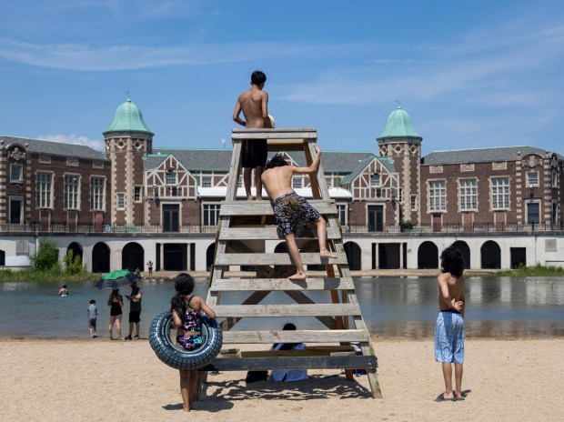 People climb on the lifeguard stand at Humboldt Park Beach on June 16, 2024, with temperatures over 90 degrees. Chicago's only inland beach officially reopens Monday after a four-year closure. (Brian Cassella/Chicago Tribune)