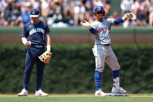 New York Mets shortstop Francisco Lindor (12) celebrates beside Chicago Cubs second baseman Nico Hoerner (2) after Lindor hit a double in the fourth inning of a game at Wrigley Field in Chicago on June 21, 2024. (Chris Sweda/Chicago Tribune)