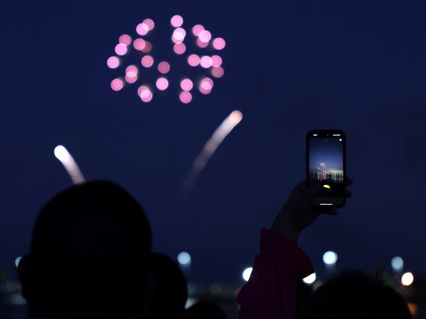People watch and record a Navy Pier biweekly fireworks display on June 26, 2024. (Chris Sweda/Chicago Tribune)