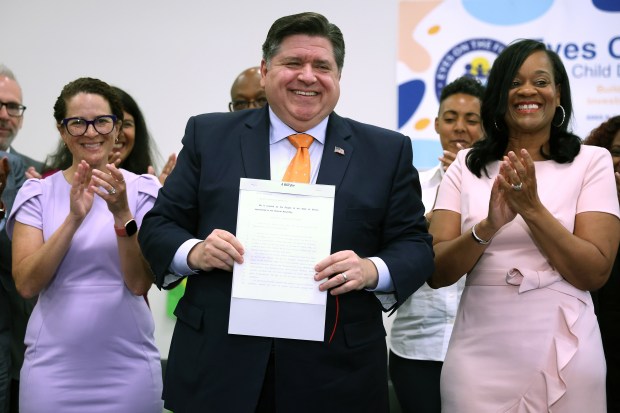 Illinois Gov. J.B. Pritzker holds up a newly signed bill at Eyes On The Future Child Development Center in Chicago establishing the Illinois Department of Early Childhood on June 25, 2024. Illinois State Rep. Mary Beth Canty (D-54th) is at left and Illinois State Sen. Kimberly A. Lightford D - 4th) is at right. (Terrence Antonio James/Chicago Tribune)
