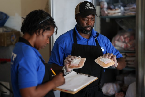 Run-A-Way Buckers farm manager Reginald Stewart lists the weights of pieces of chicken for his sister, Odell Collins, as they prepare bags of meat at their family's farm in Pembroke Township to distribute to the community on May 22, 2024. (Eileen T. Meslar/Chicago Tribune)