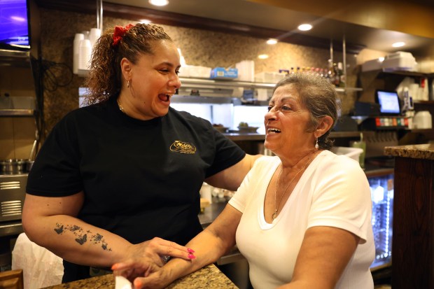 Servers Maria Gonzalez, left, and Susan Bivins laugh at 9:52 p.m. as their shifts intersect at the Golden Apple on June 22, 2024. Gonzalez has worked at the restaurant for one year and Bivins has put in 30 years. (Chris Sweda/Chicago Tribune)