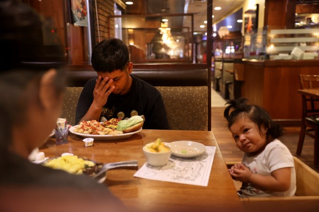 Diego Hernandez and Alexandra Lopez say grace at 11:30 p.m. before having a late dinner with their daughter, Abigail Hernandez, 18 months, at the Golden Apple in Chicago's Lakeview neighborhood on June 22, 2024. The family travels in from Buffalo Grove on occasion to dine at the restaurant. (Chris Sweda/Chicago Tribune)