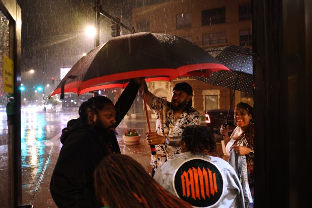 A group of diners protect themselves from rain at 11:39 p.m. upon leaving the Golden Apple in Chicago's Lakeview neighborhood, June 22, 2024. (Chris Sweda/Chicago Tribune)