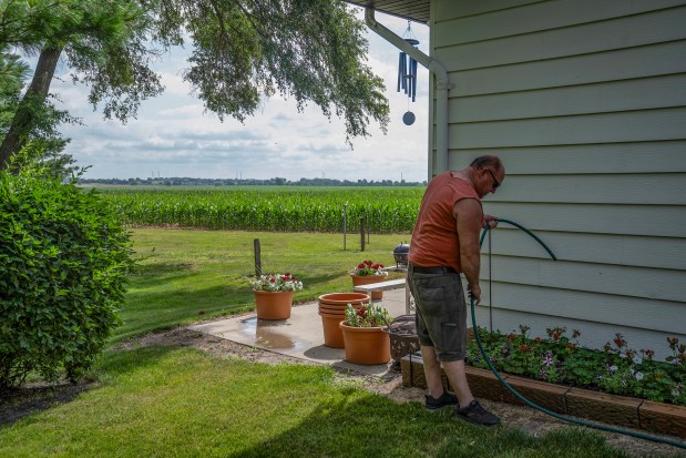 Don Underhill waters his garden in the backyard of his home on Sand Ridge Road in Morris, overlooking corn grown on CN property that will be developed into an intermodal facility, June 18, 2024. (E. Jason Wambsgans/Chicago Tribune)