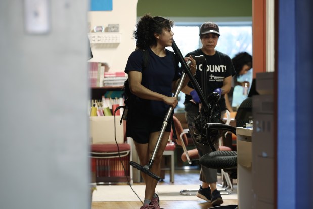 Simone Peña Hernandez uses a backpack vacuum while helping to clean an office with her family, including her mother, Beatrice, center right, and sister, Zianya, right, June 13, 2024, in Chicago. (John J. Kim/Chicago Tribune)