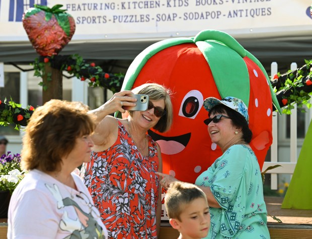 Taking a selfie in front of a photo opportunity strawberry are, from left, Sharon Convalle of Darien and Patti Reinhart of Lake County, posing on Robert Parker Coffin Road at the Friday opener of the Historic Downtown Long Grove Strawberry Fest on June 21, 2024. (Karie Angell Luc/Lake County News-Sun)