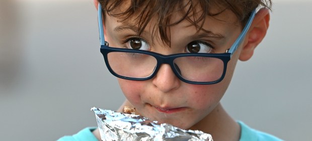 Max Filippov of Long Grove, 7, a rising second-grader, noshes on a chocolate covered banana at the Friday opener of the Historic Downtown Long Grove Strawberry Fest on June 21, 2024. (Karie Angell Luc/Lake County News-Sun)