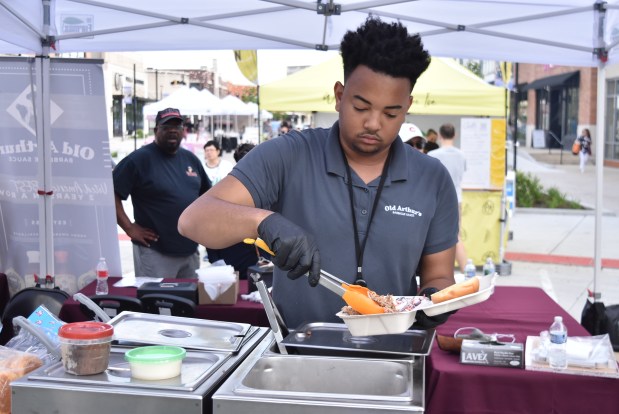 Eudell Watts V serves up a barbecue sandwich at the Old Arthur's food tent. (Jesse Wright for the Pioneer Press)