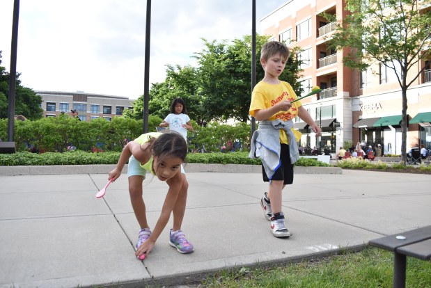 From left, Maddie Corella and Max Mason, both 7, balance eggs as part of a race while nearby their parents enjoy the cool summer evening in Burr Ridge. (Jesse Wright for the Pioneer Press)