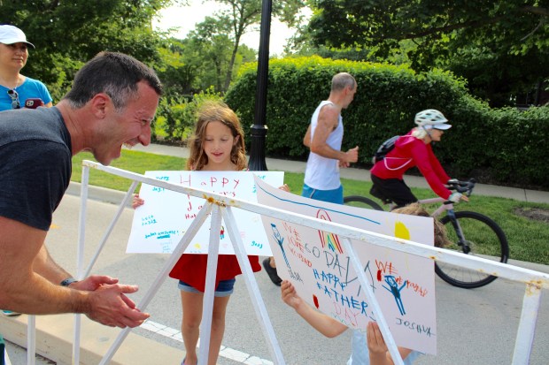 Evanstonian Bryant Greening was met at the races end by his family with celebratory signs for Father's Day. 8-year-old Mia Greening, 4-year-old Jordan Greening and wife Kelly Greening, celebrating Bryant as he races to the finish line in the Ricky Byrdsong Memorial Race Against Hate. (Gina Grillo/Pioneer Press)