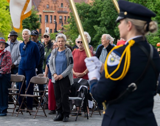 A crowd of people watch as the flags are retired by the Oak Park Police Department Honor Guard Unit at the end of a Memorial Day ceremony at Scoville Park in Oak Park on Monday, May 27, 2024. (Nate Swanson/for the Pioneer Press)