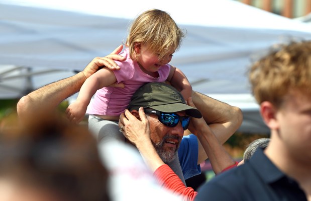 Grandparents Skip and Merle Shein of Glenview together lift granddaughter Aria, 2, from the shoulders of her grandfather at the opener of the Northbrook Farmers Market in downtown Northbrook on June 19, 2024. (Karie Angell Luc/Pioneer Press)