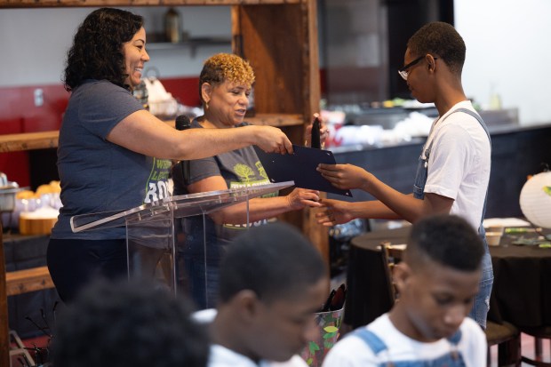 Graduate Matthew Williams is presented his degree by directors Krystal Madden, on left, and Freida Graves during a graduation ceremony for Faith Farm and Orchard's Next Urban Ag Generation class on Saturday, June 1, 2024. (Kyle Telechan/for the Post-Tribune)