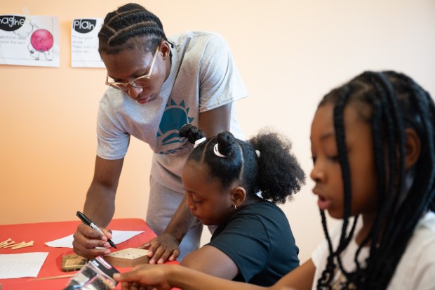 Summer Learning Lab teacher Spencer Redding helps Jurnee Vaulx, 8, mark spots to drill on a board during a Northwest Summer Learning Lab event in partnership with the Urban League of NWI at HOME Mentoring and Tutoring in Gary on Monday, June 24, 2024. (Kyle Telechan/for the Post-Tribune)