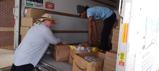 Cause 4Paws volunteers Jim Dillion (left) and Devin Singh unpack pet food and other donations during a recent Pet Food Pantry. (Sue Ellen Ross/Post-Tribune)