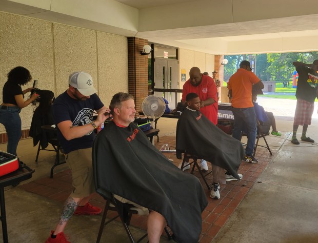 Denmark College Senior Joe Gajewski, left; and Senior Instructor Darcell Holloway, right, show off their haircutting skills on David Blue, of Valparaiso, sitting left; and Joshua Grady of Gary during PNW's Juneteenth celebration on June 19. (Michelle L. Quinn/Post-Tribune)