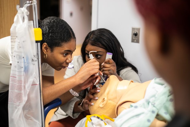 Josie Binion, a student from Payton High School, gets a look June 19, 2024, at what it's like to intubate an adult, with some help from emergency room physician Oyinkansola Okubanjo at Advocate Christ Medical Center in Oak Lawn. (Vincent D. Johnson/for the Daily Southtown)