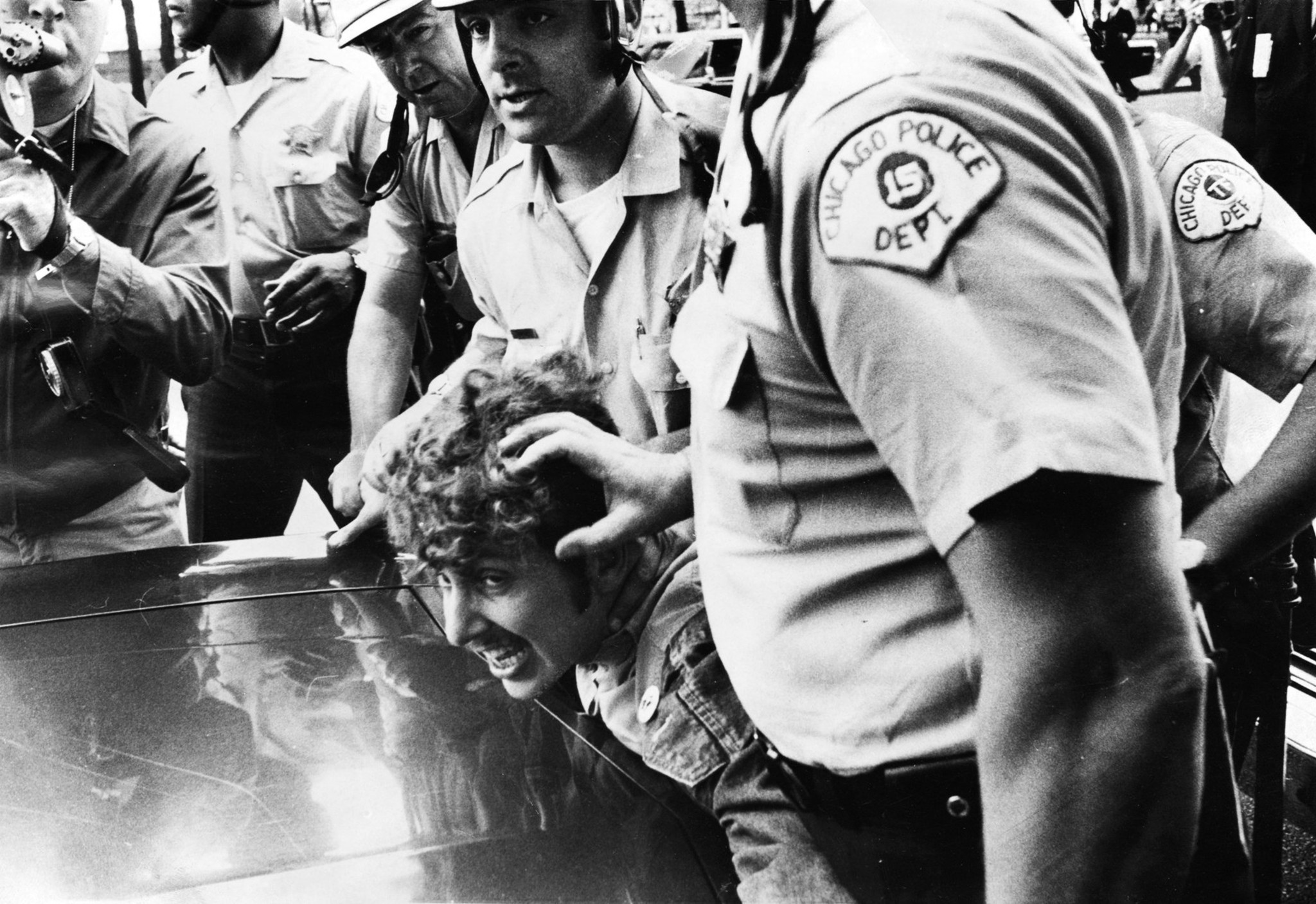 Police hold an anti-war protester over the hood of a...