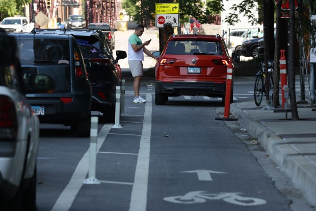 A motorist enters his vehicle parked in a bicycle lane in the 500 block of West Kinzie Street, June 29, 2022, in Chicago. (John J. Kim/Chicago Tribune)
