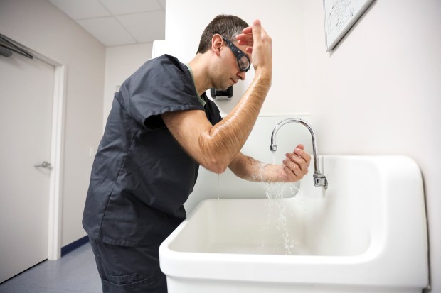 Dr. Keith Reisinger-Kindle scrubs in to a surgical abortion at Equity Clinic on May 21, 2023, in Champaign, Illinios. (Shanna Madison/Chicago Tribune)