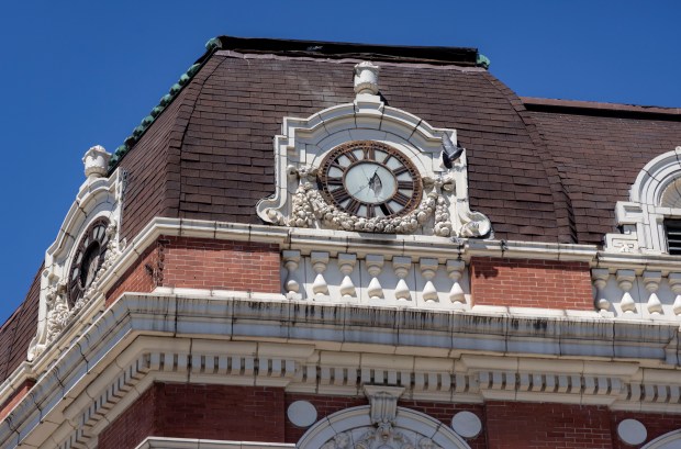 Pigeons roost near a broken clock face on the mansard roof of the Douglas Park Auditorium in North Lawndale on June 11, 2024. (Brian Cassella/Chicago Tribune)