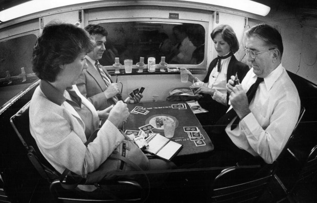 Evening commuters on the Chicago & North Western, what is now a Metra line, enjoy a drink and a game of cards on Aug. 25, 1982. (Walter Neal/Chicago Tribune)