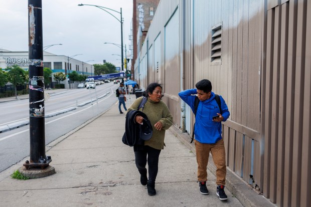 Jessica Juma and her son Luis Miguel, 15, walk outside a migrant shelter on the Lower West Side on June 4, 2024, in Chicago. When Juma's husband went missing, workers at the shelter told her they'd have to give away his cot. (Armando L. Sanchez/Chicago Tribune)