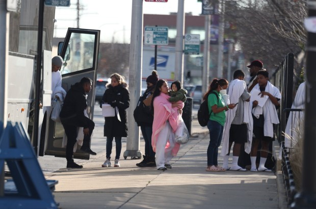 Migrants walk off a bus after arriving at Chicago's migrant landing zone at the corner of Polk and Desplaines Streets in the West Loop on Nov. 28, 2023. (Trent Sprague/Chicago Tribune)