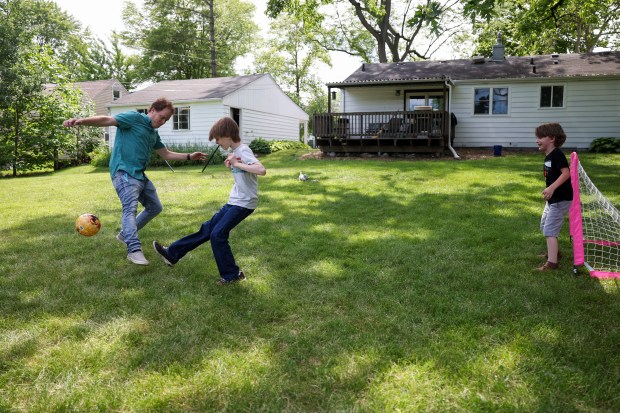 Joel Gratcyk plays with his sons Wesley, 11, center, and Theodore, 7, in their backyard in Arlington Heights on June 12, 2024. (Eileen T. Meslar/Chicago Tribune)