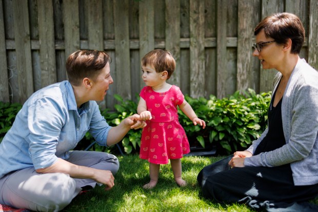 The Rev. Britt Cox, left, and wife Jessica Hager play with their 1-year-old daughter Luca at their home in Evanston. (Armando L. Sanchez/Chicago Tribune)