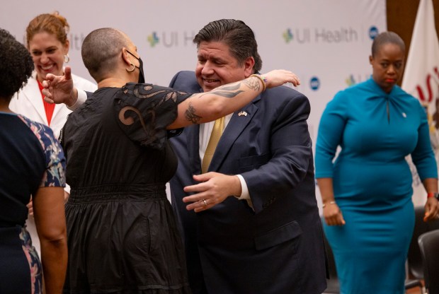 Gov. J.B. Pritzker hugs Megan Jeyifo, the executive director of the Chicago Abortion Fund, after he announced expanded reproductive health care protections on July 31, 2023 at UIC's Student Center West. (Brian Cassella/Chicago Tribune)