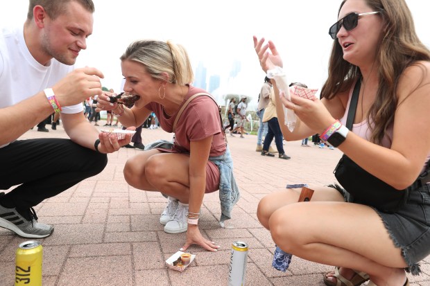 Bryan Balderson, from left, Anna Ledford, and Claire Balderson eat chicken drumsticks at the Taste of Chicago on July 8, 2022. (John J. Kim/Chicago Tribune)