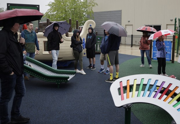 Visitors to the newly opened Treetop Community Playground stand near the roller slide. The series of tubes halts static electricity from forming, which can disrupt children with cochlear implants.(NorthBridge Church/David Latz)