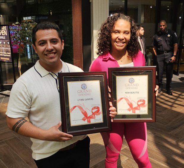 Roberto Hernandez of Aurora, owner of Utime Gamers video gaming spot, and Annette Clark, of Yorkville, owner of New Beautee, a natural body care store, show off the plaques awarded to 12 new businesses during a mass ribbon-cutting ceremony at Fox Valley Mall in Aurora Wednesday morning. (David Sharos / For The Beacon-News)