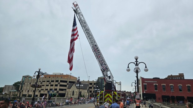 An American flag flies from the ladder of an Aurora Fire Department vehicle Thursday during the Fourth of July parade in the city's downtown. (David Sharos / For The Beacon-News)
