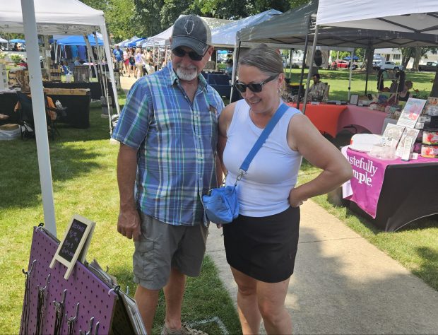 Lora Soehlke and her husband Dave of Plainfield check out one of the craft fair tents Saturday during the two-day Mid-Summer Makers Market at Town Square in Yorkville. (David Sharos / For The Beacon-News)