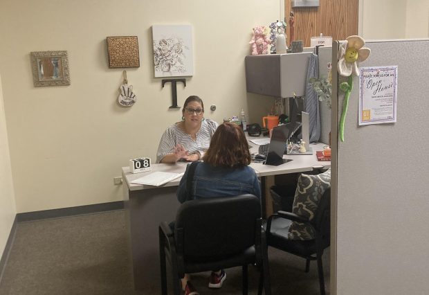 Jessica Torres, information and assistance specialist with Senior Services Associates, talks to a client on Monday at the agency's Aurora center, 2111 Plum St. (Denise Crosby)