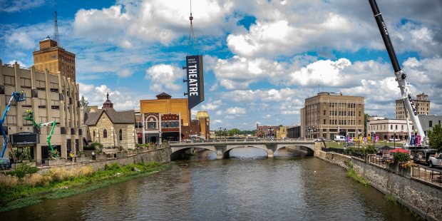 The sign for the new Stolp Island Theatre is lifted by crane across the Fox River in downtown Aurora Monday to be installed outside the theater at 5 E. Downer Place, Suite G. (Thomas J. King)