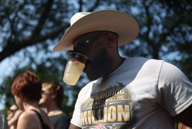 Daylen Chambliss holds a drink with his teeth to free up his hands while watching Doss perform during Pitchfork Music Festival at Union Park Friday, July 19, 2024, in Chicago. (John J. Kim/Chicago Tribune)