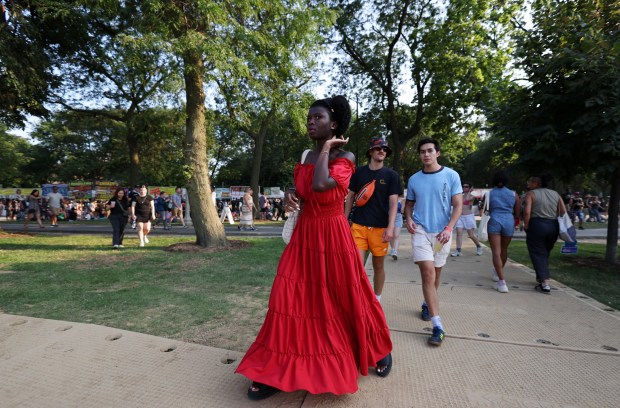 A woman in a red dress walks through the grounds during Pitchfork Music Festival at Union Park Friday, July 19, 2024, in Chicago. (John J. Kim/Chicago Tribune)