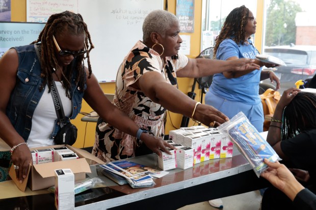 Outreach worker Lynn Stevenson, Director of Substance Abuse Services, left, Walonza Lee and Keisha House, assistant director, nurse practitioner, hand out drug testing kits and Narcan during a talk about substance abuse and a demonstration of how to administer Narcan on a person who experiences overdose, at Larry's Barber College on July 9, 2024. (Antonio Perez/Chicago Tribune)