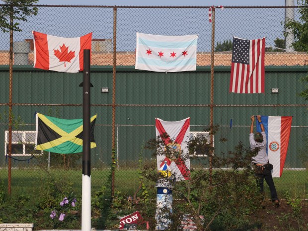 Robert Bulanon, who is homeless and has been living in the homeless encampment for a couple of years, hangs one of the flags at his homeless encampment he shares with one other person along the river, adjacent to Northside College Prep on July 30, 2024, as Streets and Sanitation workers prepare to clear the area along the river. (Antonio Perez/Chicago Tribune)