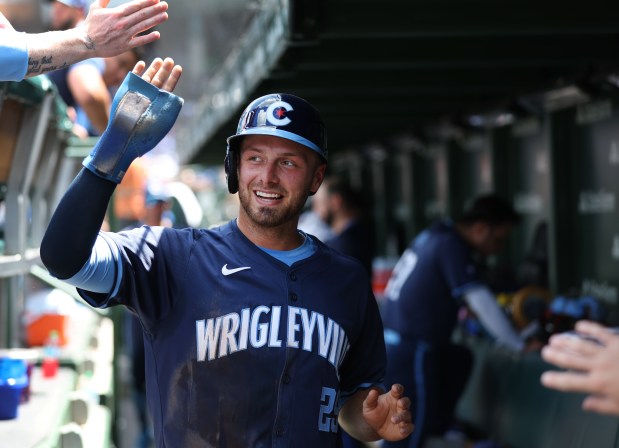 Cubs first baseman Michael Busch is congratulated in the dugout after scoring on a single by Ian Happ in the third inning on July 5, 2024, at Wrigley Field. (Chris Sweda/Chicago Tribune)