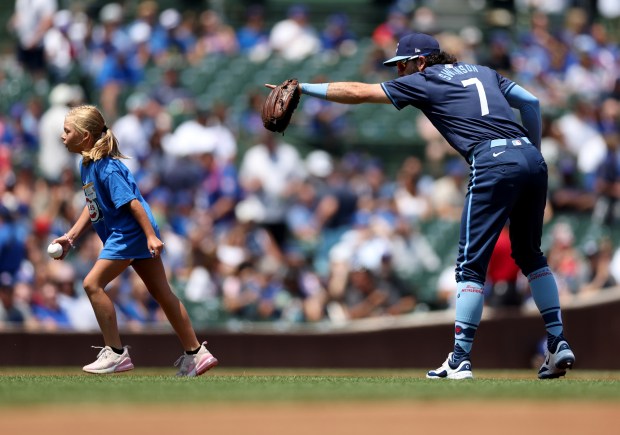 Cubs shortstop Dansby Swanson guides a young fan back off the field after kids of season ticket holders received autographs from Cubs players before the game on July 19, 2024, at Wrigley Field. (Chris Sweda/Chicago Tribune)