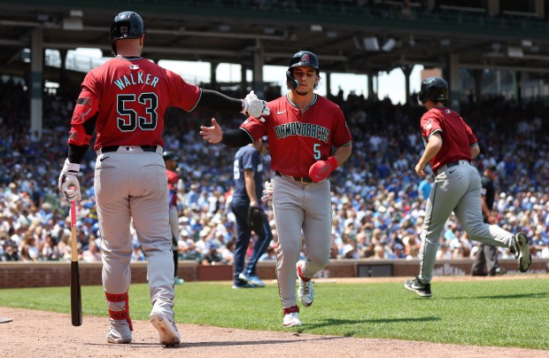 Diamondbacks outfielder Alek Thomas (5) is congratulated by teammate Christian Walker (53) after Thomas scored in the third inning against the Cubs on July 19, 2024, at Wrigley Field. (Chris Sweda/Chicago Tribune)