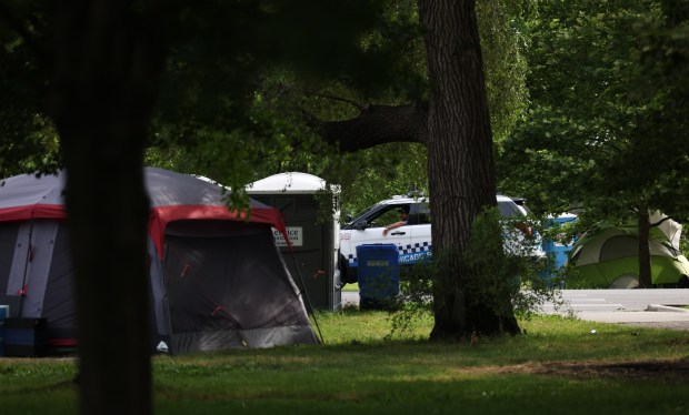 A police officer patrols through a tent encampment in the northeast corner of Humboldt Park, June 26, 2024, in Chicago. (John J. Kim/Chicago Tribune)