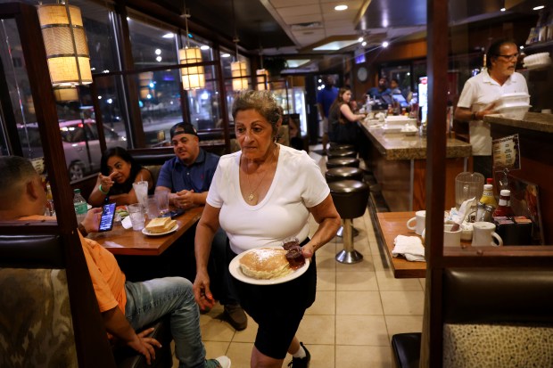 Server Susan Bivins delivers an order of pancakes at 9:59 p.m. at the Golden Apple Grille & Breakfast House on June 22, 2024. Bivins has worked at the restaurant for 30 years. (Chris Sweda/Chicago Tribune)